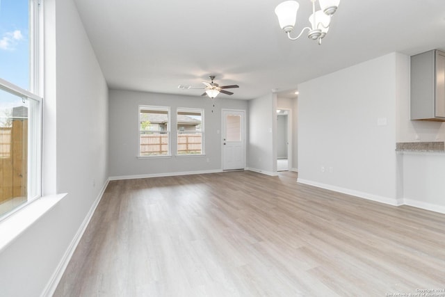 unfurnished living room with light wood finished floors, baseboards, and ceiling fan with notable chandelier