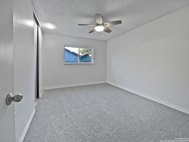 unfurnished bedroom with a ceiling fan, carpet, a textured ceiling, and baseboards