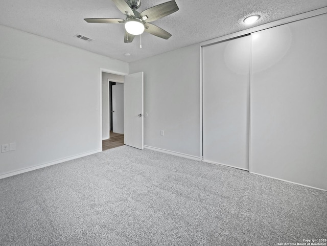 unfurnished bedroom featuring visible vents, a ceiling fan, a textured ceiling, carpet flooring, and a closet