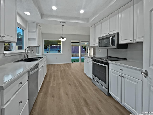 kitchen featuring a sink, visible vents, white cabinets, appliances with stainless steel finishes, and a tray ceiling