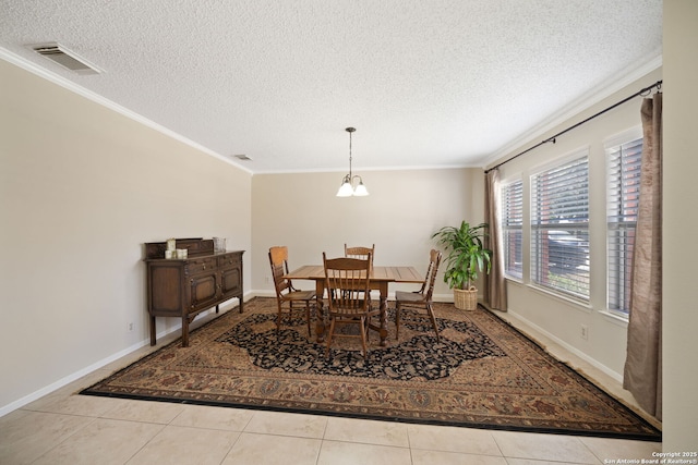 tiled dining space with ornamental molding, visible vents, a textured ceiling, and baseboards