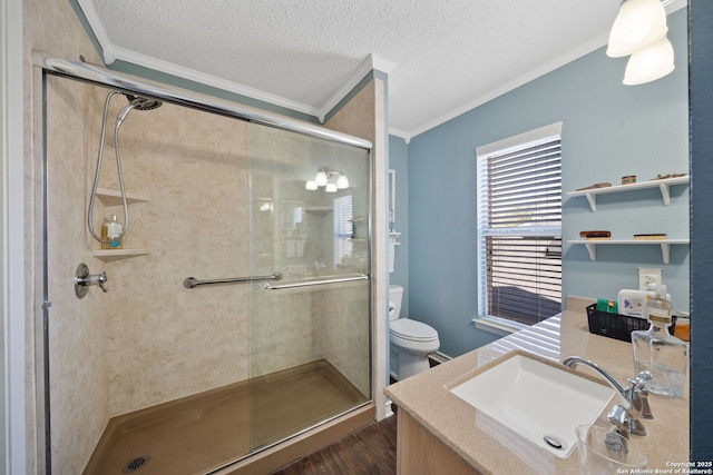 bathroom with a textured ceiling, toilet, wood finished floors, a stall shower, and crown molding