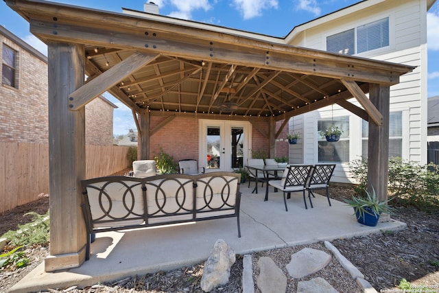 view of patio with a gazebo, fence, outdoor dining area, and french doors