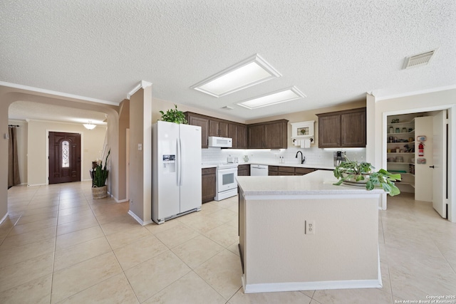 kitchen with dark brown cabinetry, white appliances, a sink, visible vents, and light countertops