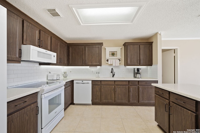 kitchen featuring white appliances, light tile patterned floors, visible vents, light countertops, and a sink