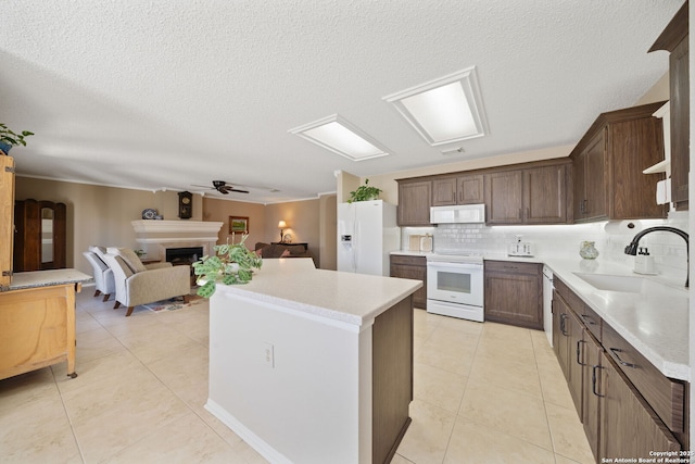 kitchen featuring white appliances, a fireplace, light tile patterned floors, and a sink