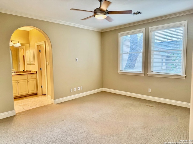 unfurnished room featuring arched walkways, light colored carpet, visible vents, ornamental molding, and baseboards