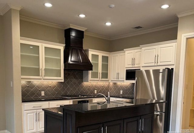 kitchen featuring an island with sink, white cabinetry, premium range hood, and appliances with stainless steel finishes