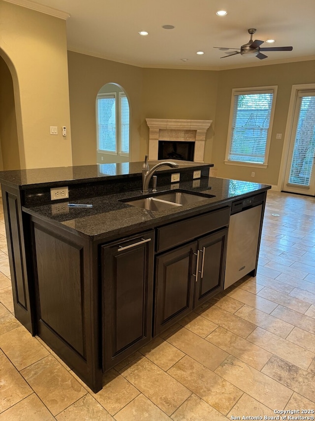 kitchen with open floor plan, a sink, a kitchen island with sink, a fireplace, and stainless steel dishwasher