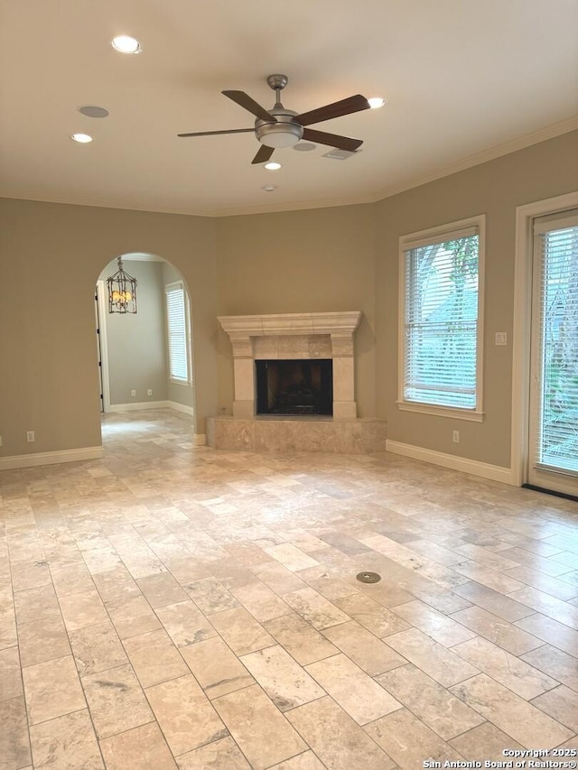 unfurnished living room featuring arched walkways, recessed lighting, a ceiling fan, a tile fireplace, and baseboards