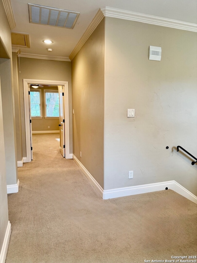 hallway featuring visible vents, attic access, ornamental molding, light carpet, and baseboards