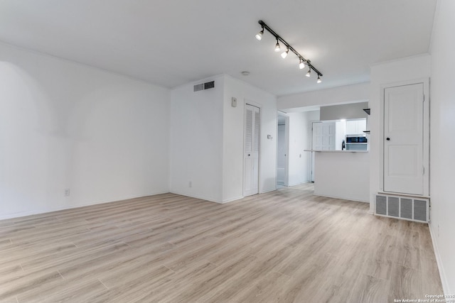 empty room featuring light wood-type flooring, rail lighting, and visible vents