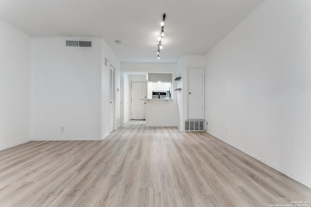 empty room featuring light wood-type flooring, visible vents, and baseboards