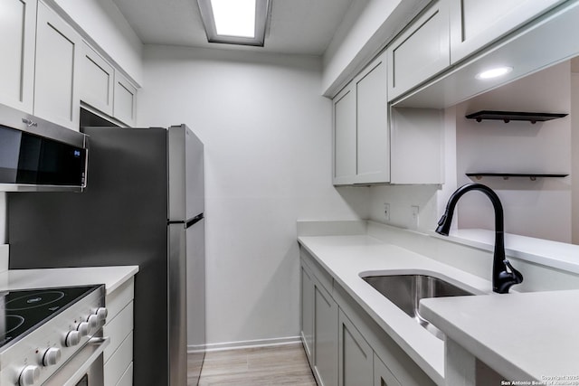 kitchen featuring stainless steel appliances, light wood-type flooring, a sink, and light countertops