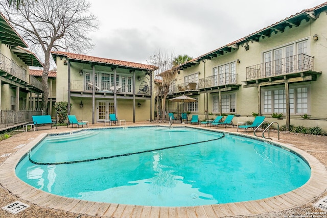 pool with fence, french doors, and a patio