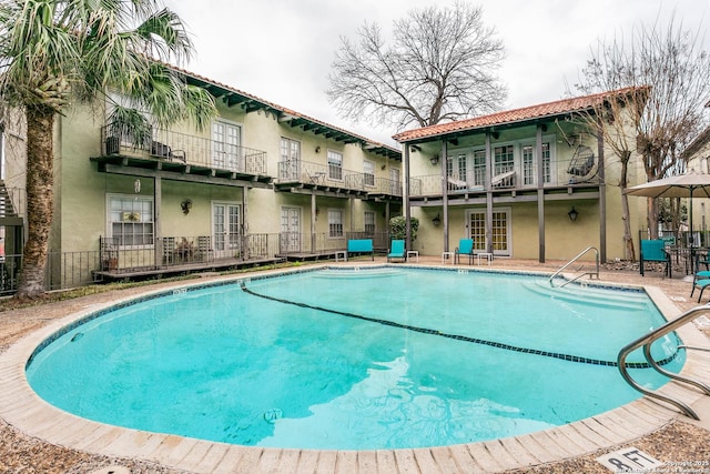 pool with a patio area, fence, and french doors