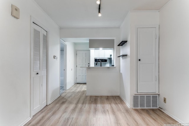 corridor with baseboards, light wood-type flooring, visible vents, and crown molding