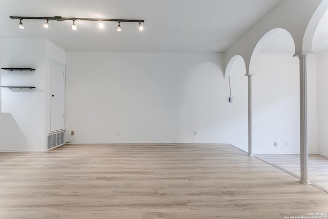 spare room featuring light wood-type flooring, visible vents, and arched walkways