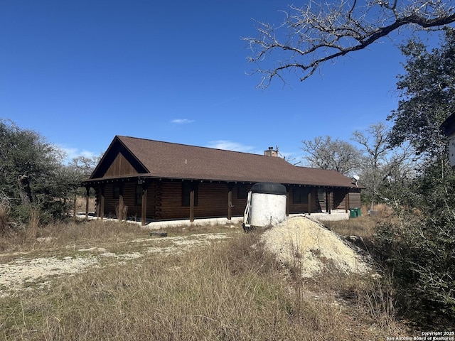 exterior space featuring a chimney and log siding