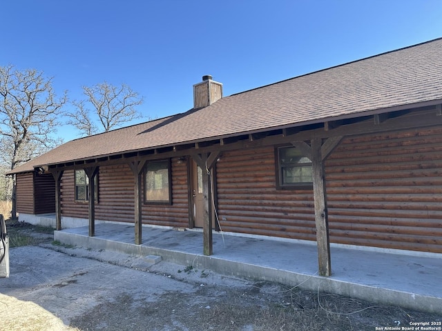 view of property exterior with a shingled roof and a chimney