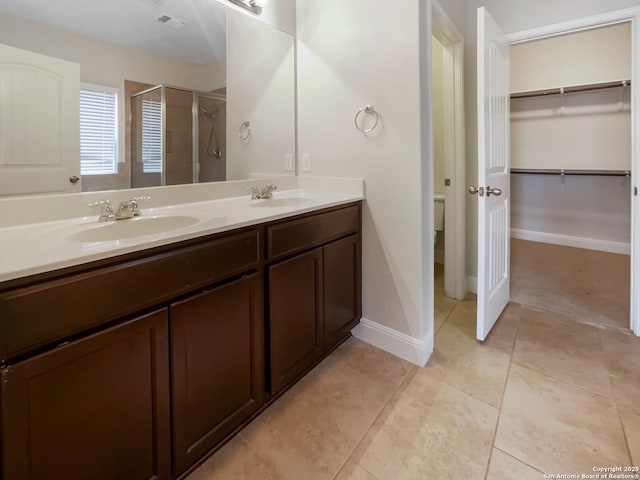 full bathroom with double vanity, a stall shower, tile patterned flooring, and a sink