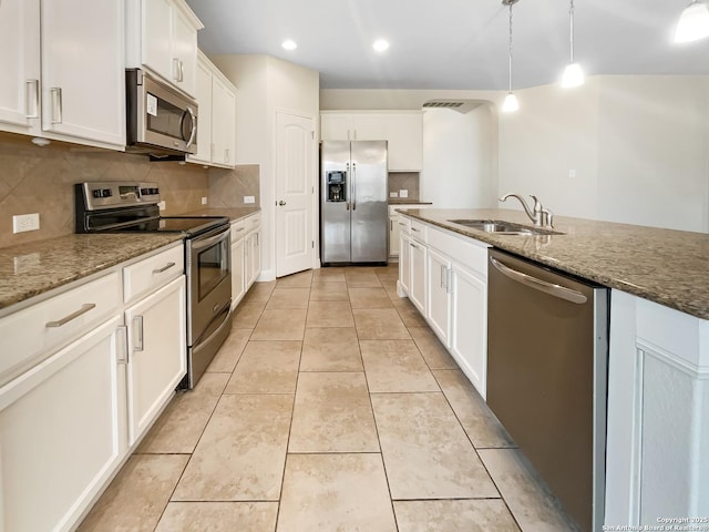 kitchen with stone countertops, stainless steel appliances, a sink, and light tile patterned flooring