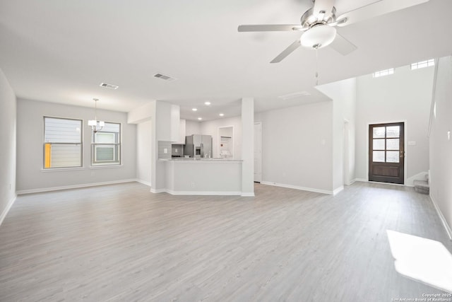 unfurnished living room with light wood-type flooring, baseboards, visible vents, and ceiling fan with notable chandelier