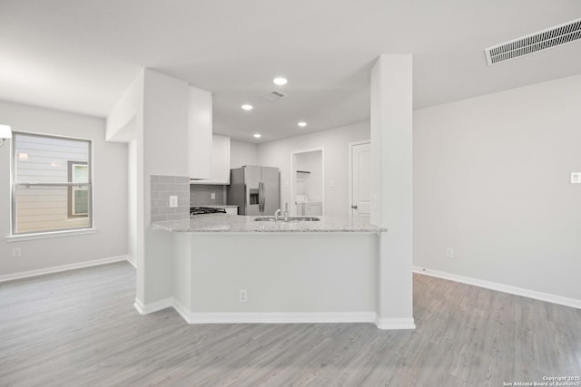 kitchen with visible vents, backsplash, light wood-style floors, white cabinetry, and stainless steel fridge with ice dispenser