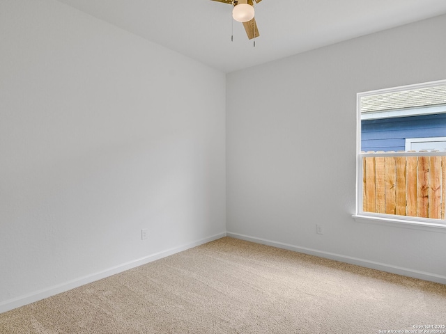 carpeted empty room featuring a healthy amount of sunlight, ceiling fan, and baseboards