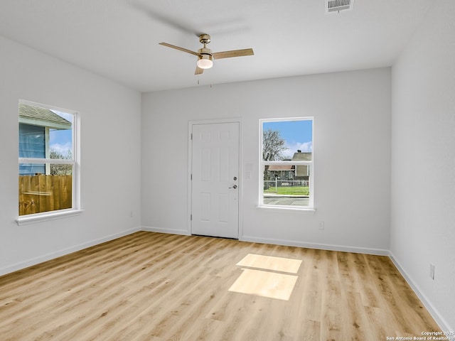 spare room featuring ceiling fan, plenty of natural light, wood finished floors, and baseboards