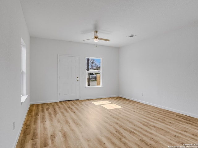 empty room featuring light wood-type flooring, visible vents, and baseboards