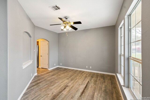 spare room with baseboards, wood finished floors, and a healthy amount of sunlight