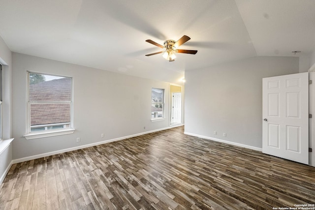 spare room with vaulted ceiling, dark wood finished floors, a ceiling fan, and baseboards