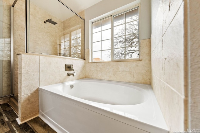 full bathroom featuring tile walls, a garden tub, a shower stall, and wood finished floors