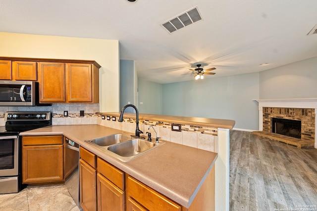 kitchen featuring visible vents, open floor plan, a sink, stainless steel appliances, and backsplash