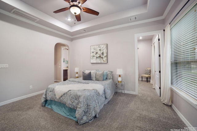 bedroom featuring a tray ceiling, visible vents, and arched walkways