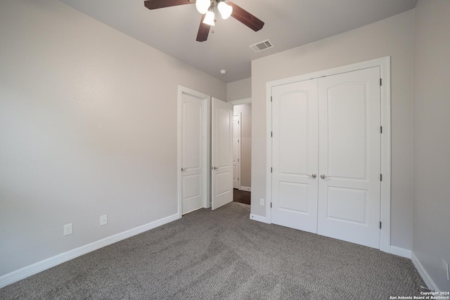 unfurnished bedroom with a closet, visible vents, dark carpet, and baseboards