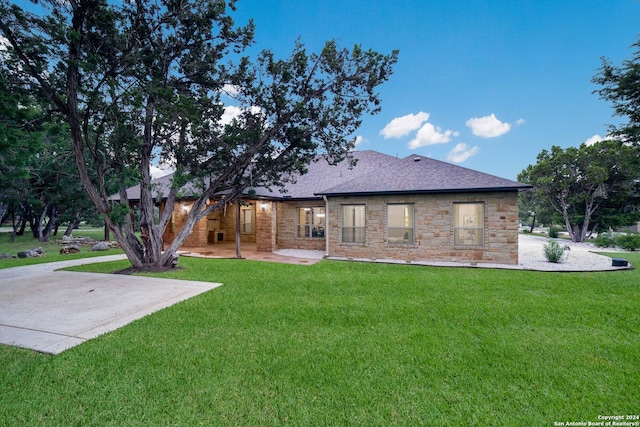 back of property featuring a patio, a lawn, and roof with shingles