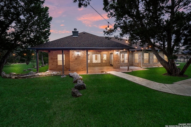 back of house featuring a shingled roof, a chimney, a patio, and a yard