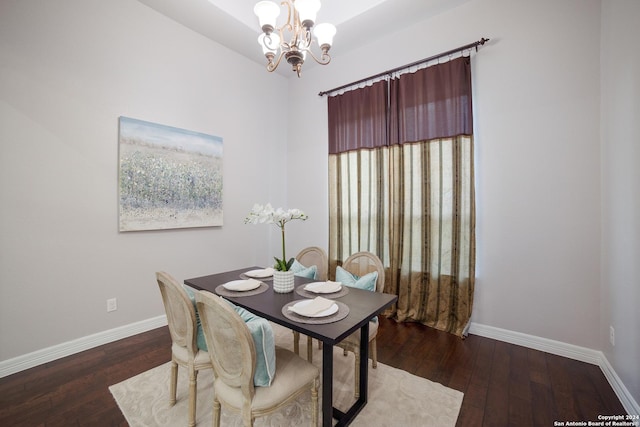 dining space featuring wood-type flooring, an inviting chandelier, and baseboards