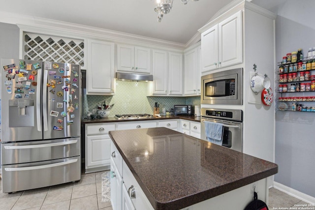 kitchen with stainless steel appliances, white cabinets, under cabinet range hood, and tasteful backsplash