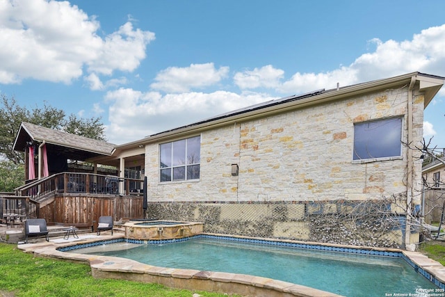 back of house featuring stone siding, an outdoor pool, and an in ground hot tub