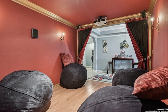 home theater room featuring ornamental molding, arched walkways, baseboards, and wood finished floors