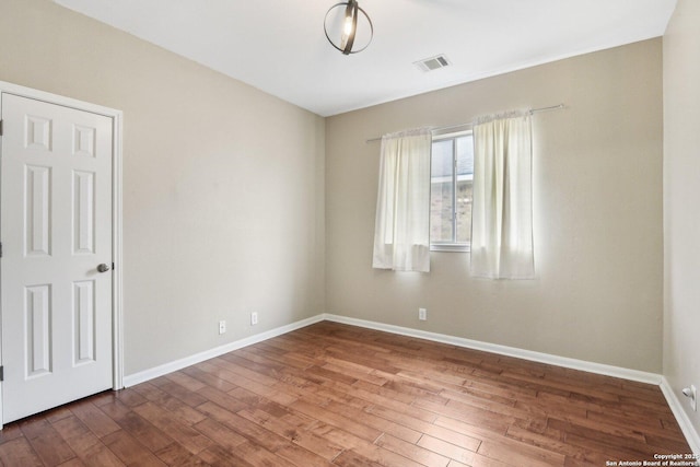 empty room with visible vents, baseboards, and wood finished floors