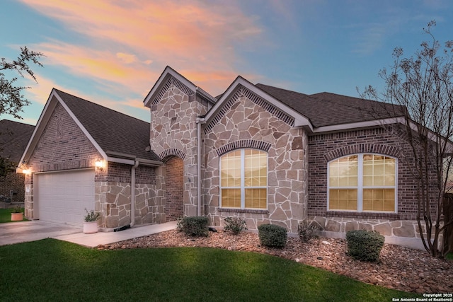 french country style house with stone siding, roof with shingles, an attached garage, and concrete driveway