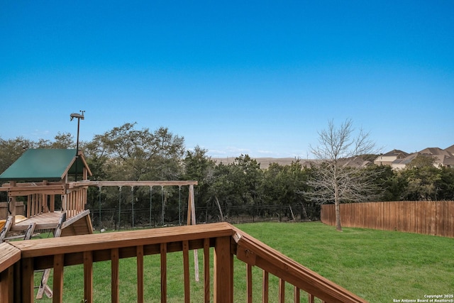 wooden deck featuring a yard, a playground, and a fenced backyard