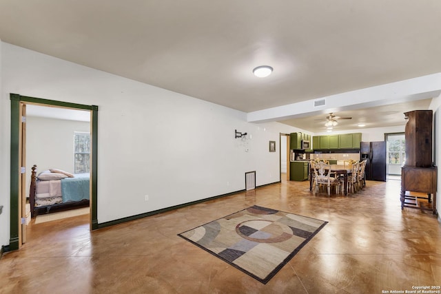 living room with a ceiling fan, visible vents, and baseboards