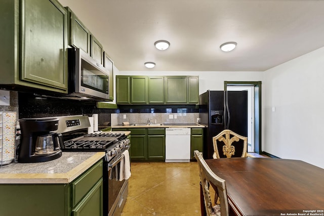 kitchen featuring stainless steel appliances, a sink, light countertops, tasteful backsplash, and green cabinetry