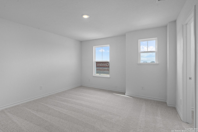 empty room with light carpet, baseboards, and a wealth of natural light