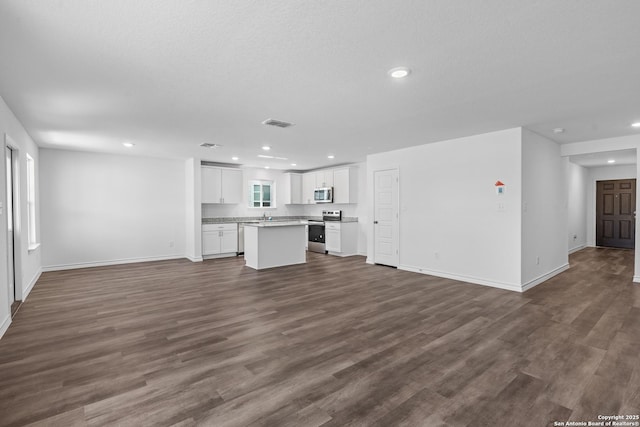 unfurnished living room with baseboards, dark wood finished floors, visible vents, and recessed lighting
